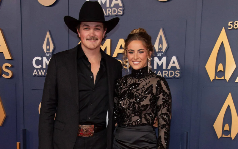 Zach Top and Amelia Taylor making their red carpet debut at the 2024 CMA Awards, Zach dressed in a black suit and hat while Amelia stuns in a black dress, confirming their relationship publicly for the first time.