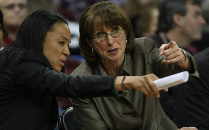 This image features Dawn Staley and her assistant coach, Lisa Boyer, on the sidelines during a game, highlighting their strong professional partnership and teamwork in women's basketball.