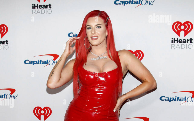 This image shows Justina Valentine flashing a bright smile while walking the red carpet at an event, exuding confidence and charm. The photo is featured in an article exploring the question, "Who is Justina Valentine dating?" highlighting her public persona and the mystery around her romantic life.